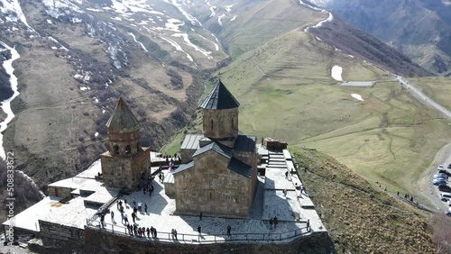 Camera drone flies around Holy Trinity Church (Gergeti Trinity Church) near the village of Stepantsminda in Georgia photo