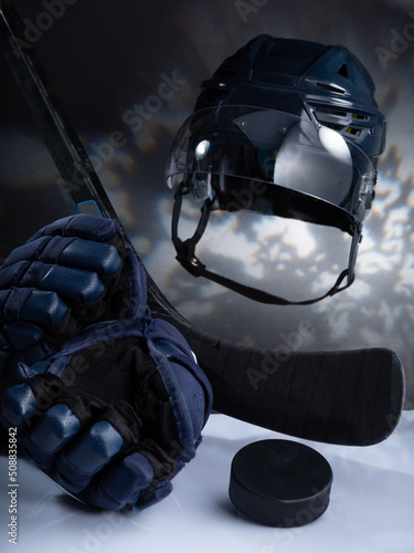 Closeup of ice hockey equipment against a dark background. Ice hockey helmet, stick, puck and gloves photo