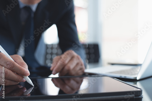 Fotobehang Businessman using stylus pen signing e-document on digital tablet with laptop co