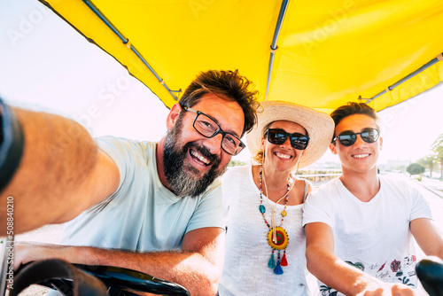 Enjoyed happy family father mother son have fun together on a surrey bikie. Outdoor leisure activity group of different ages caucasian people. Man woman and boy enjoy summer vacation photo