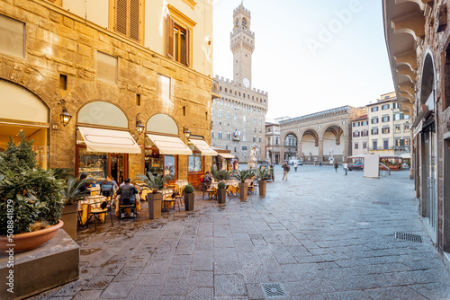 Beautiful street with cafe terrace near central square in Florence city, Italy. Vecchio palace with tower on the background. Traveling italian landmarks concept