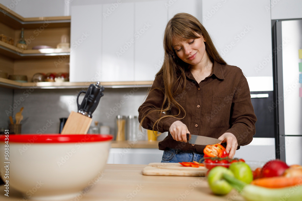 Happy young woman on modern kitchen cutting vegetables. Cooking process Happy young woman on modern kitchen cutting vegetables. Cooking process