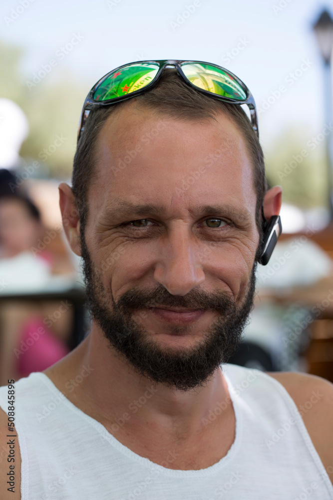 Selective focus photography of the handsome American bearded Fashion man wearing sunglasses Looks At You. Russian guy smiling self-confidently look camera. Hipster Caucasian man with natural face Selective focus photography of the handsome American bearded Fashion man wearing sunglasses Looks At You. Russian guy smiling self-confidently look camera. Hipster Caucasian man with natural face
