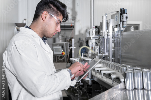 Factory worker inspecting production line on beverage factory with computer tablet. High quality photo