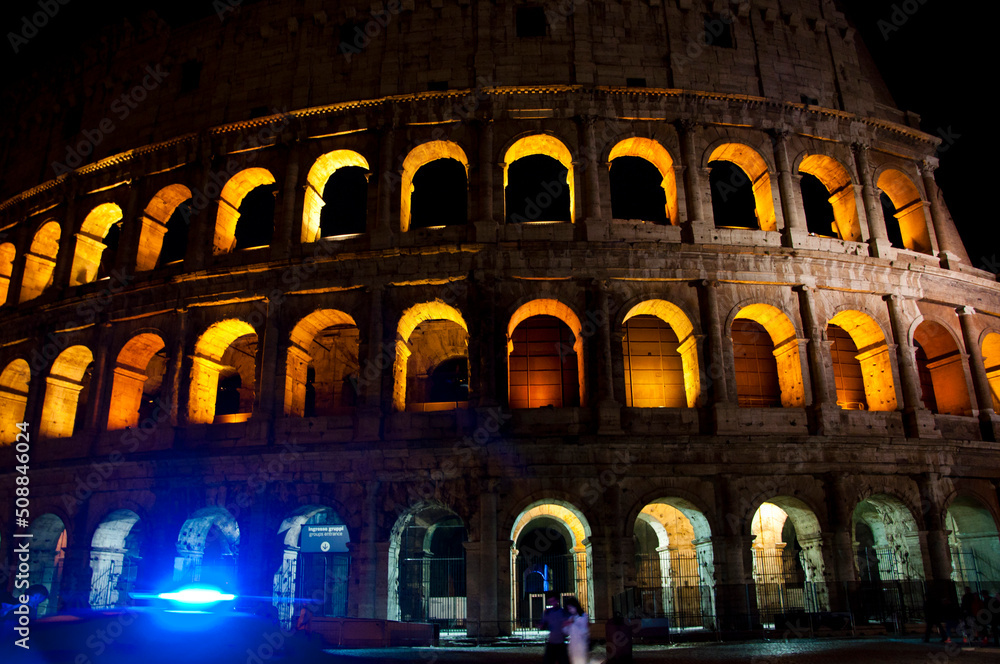 Exterior of ancient Coliseum amphitheatre architecture lit up at night in Rome, Italy
