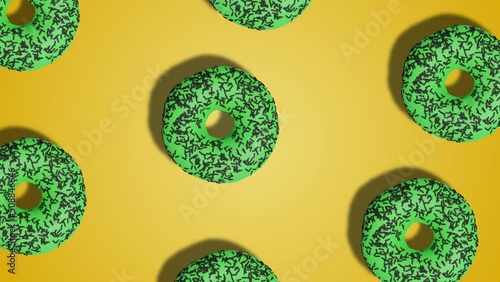 Simple motion design, pattern of green glazen donuts on yellow abstract background. Stop motion animation. Seamless looping photo