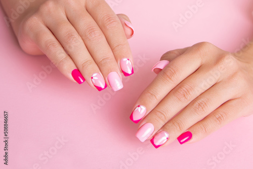 Beautiful female hands with fashion manicure nails, flowers design, pink gel polish