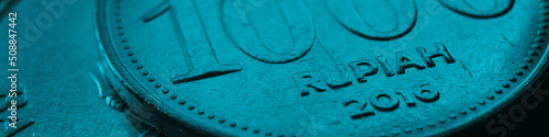 1000 Indonesian rupiah. Fragment of textured coin. Teal tinted header. Dark banner about economy or finance. Coins and money of Indonesia. News on banking and business theme. Macro