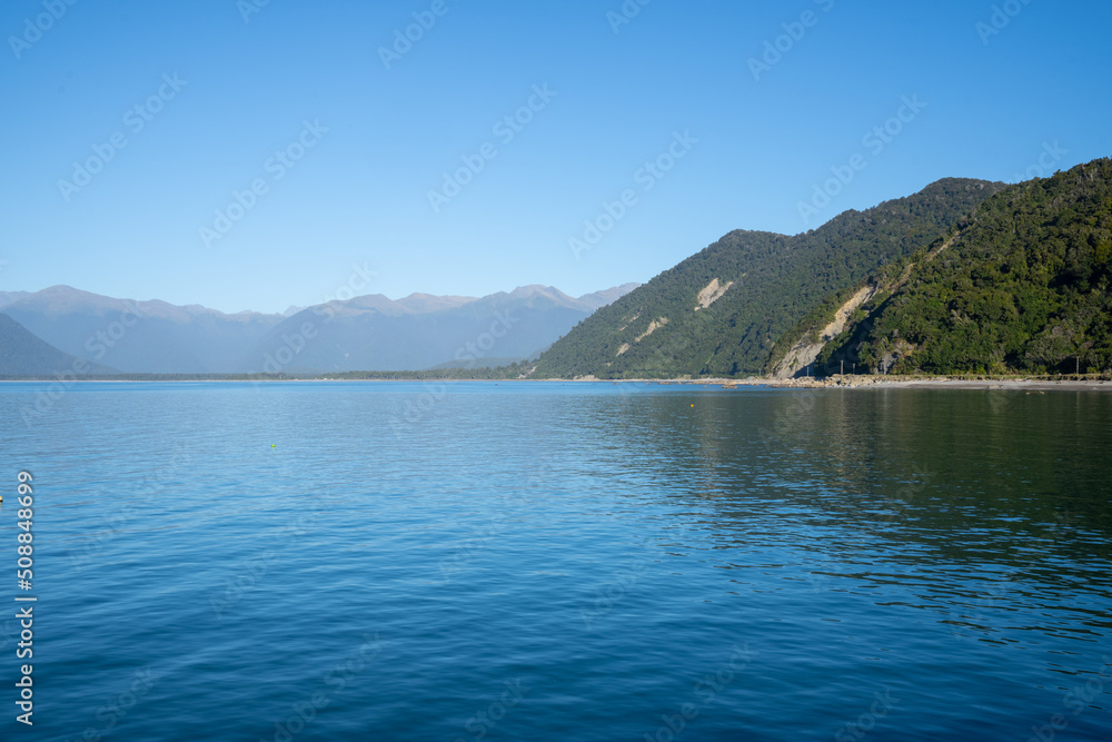 Scenes blue water of Jackson Bay surrounded by Southern Alps mountains