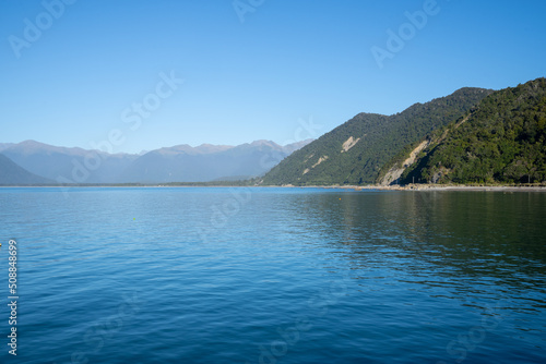 Scenes blue water of Jackson Bay surrounded by Southern Alps mountains © Brian Scantlebury