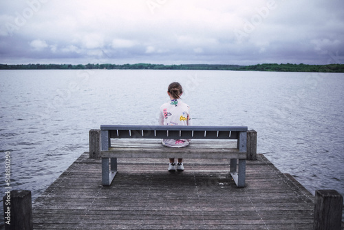 Chica sentada a solas en un embarcadero. photo