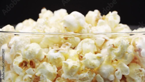 Pour Popcorn into a rotating glass on a Black background.
