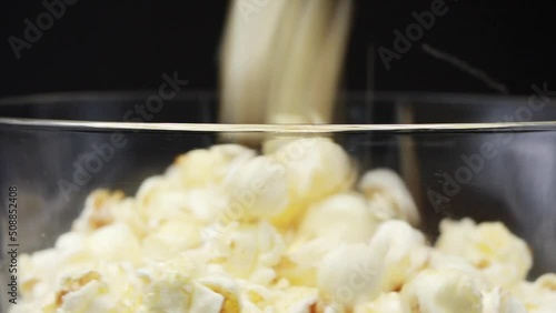 Pour Popcorn into a rotating glass on a Black background.
