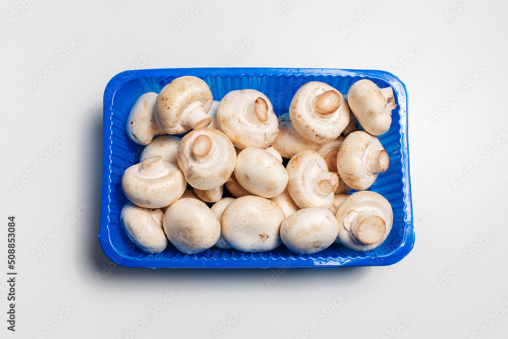 Top view of plastic box with champion mushrooms on white background. Top view of plastic box with champion mushrooms on white background.