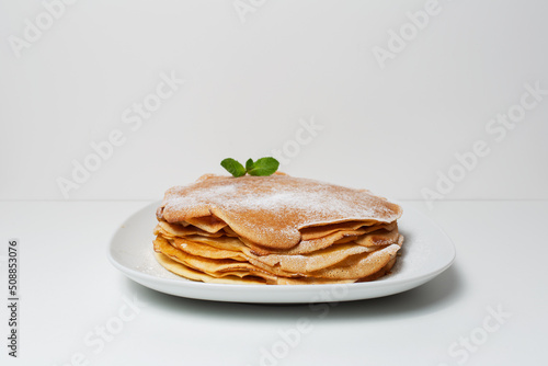 Close-up of plate with vegan thin pancakes, on light grey background.