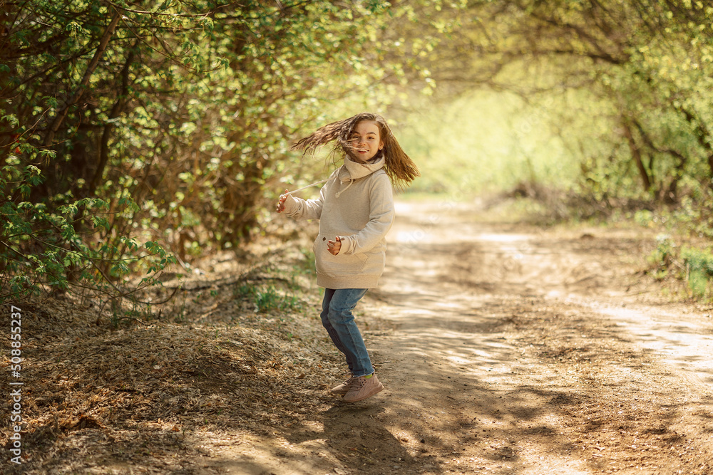 Little pretty girl on walk in sunny spring park. Fairy forest. Child with long hair listens to music, sings, smiles and rejoices. High quality photo Little pretty girl on walk in sunny spring park. Fairy forest. Child with long hair listens to music, sings, smiles and rejoices. High quality photo