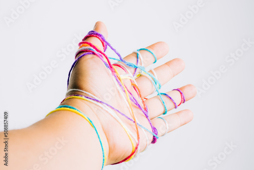 Hand wrapped with wool or yarn of multiple colors reaching towards something. Conceptual.