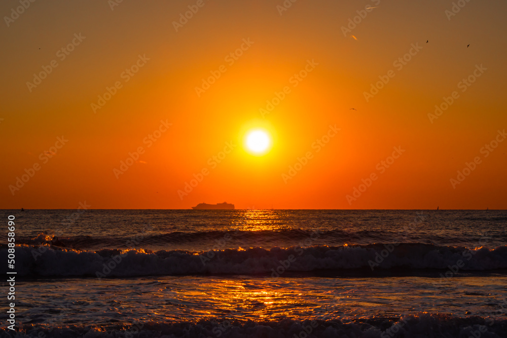 Sunset over the Mediterranean Sea with a large passenger ship in the background