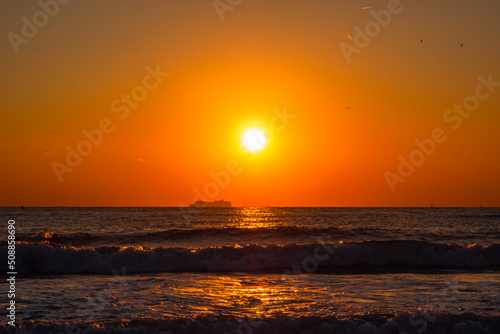 Sunset over the Mediterranean Sea with a large passenger ship in the background