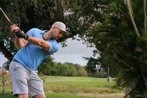 a golfer hitting a ball through a gap of trees