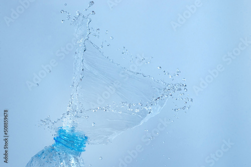 Bottle of water splash isolated on blue background