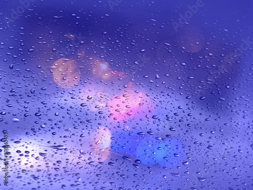 rain drops on windows and street traffic evening light bokeh blurred on wet asphalt season colorful background