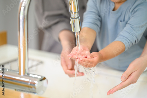 Toddler washing hands with mom Copy space