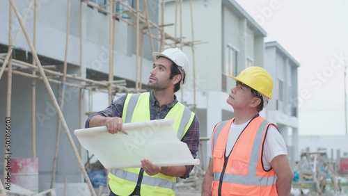 Professional male civil engineer or Architect with contractor, foreman worker. While look at blueprint discuss meeting success building project and pointing with hand shake on construction site.