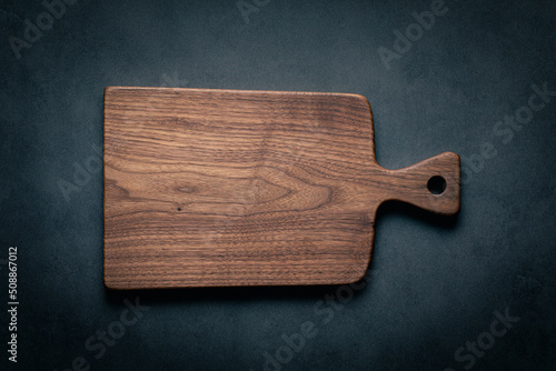 Fotografering A handcrafted black walnut wood chopping board sits on a dark-toned tabletop