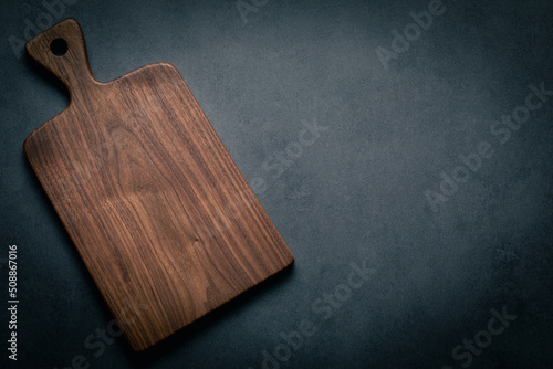Papier peint A handcrafted black walnut wood chopping board sits on a dark-toned tabletop