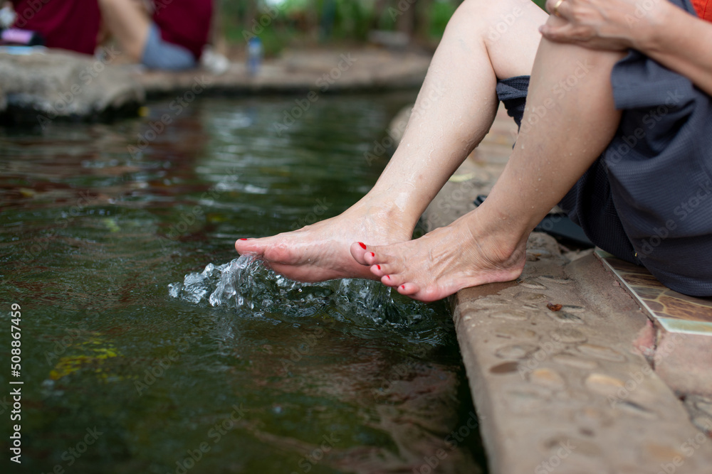 A happy asian young woman relaxing in a hot spring and using her foot to bail out the water. A happy asian young woman relaxing in a hot spring and using her foot to bail out the water.