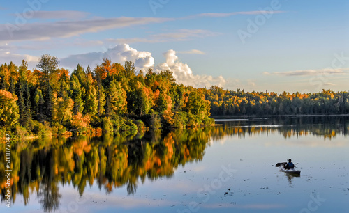 Kayaker admiring the spectacular Autumn Colors on a Lake in Alaska