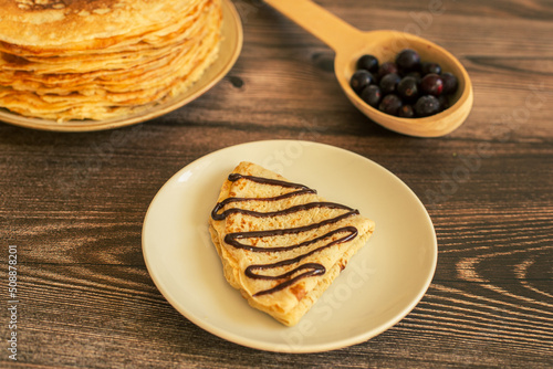 Delicious pancakes with chocolate sauce fresh blueberries on a rustic wooden table. Rustic brown table. 