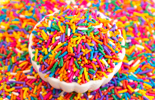 A Bowl of Rainbow Sprinkles on a Table of Sprinkles