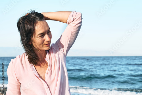 Portrait of happy middle aged woman enjoying on sea. Wellness, success, freedom and travel concept. Trip in summertime.