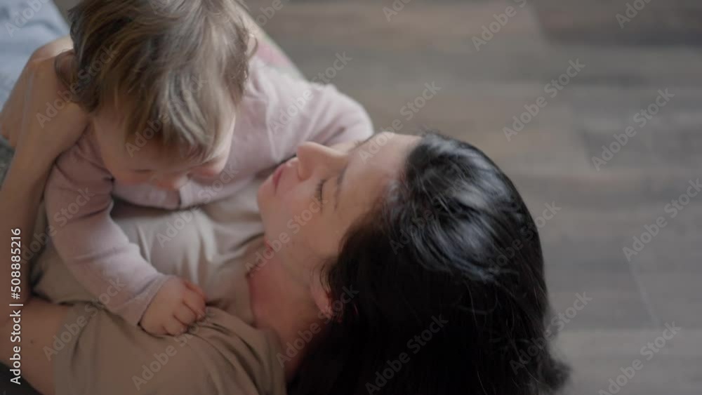 Happy carefree mother and cute small child daughter tickling laughing having fun lying on sofa and playing, smiling mum enjoying bonding cuddling hugging spending time with little funny kid at home Happy carefree mother and cute small child daughter tickling laughing having fun lying on sofa and playing, smiling mum enjoying bonding cuddling hugging spending time with little funny kid at home