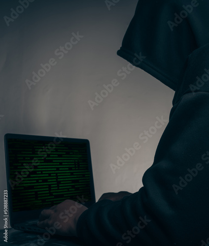 The hacker was wearing a black hoodie. Stealing huge financial data on computers with binary code digital interface.Hacking and malware concept.