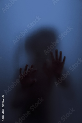 Ghost concept shadow of a child behind the matte glass blurry hand and body soft focus