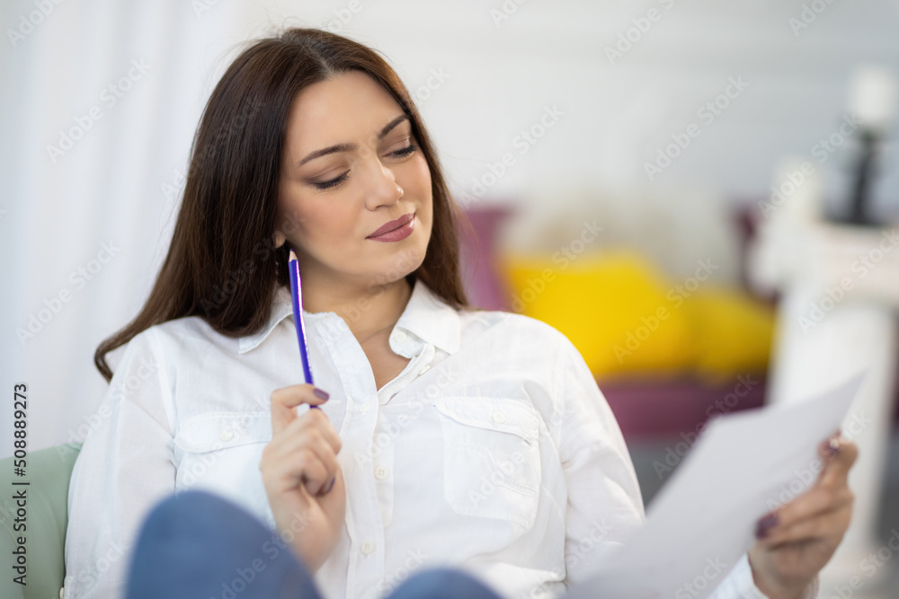 A girl in a shirt sits near the table and draws ideas on paper and in a notebook in the room A girl in a shirt sits near the table and draws ideas on paper and in a notebook in the room