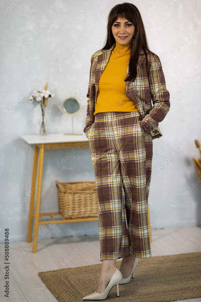 Fototapeta premium Model in a pantsuit and golf and a notebook in her hands against a gray wall in the studio