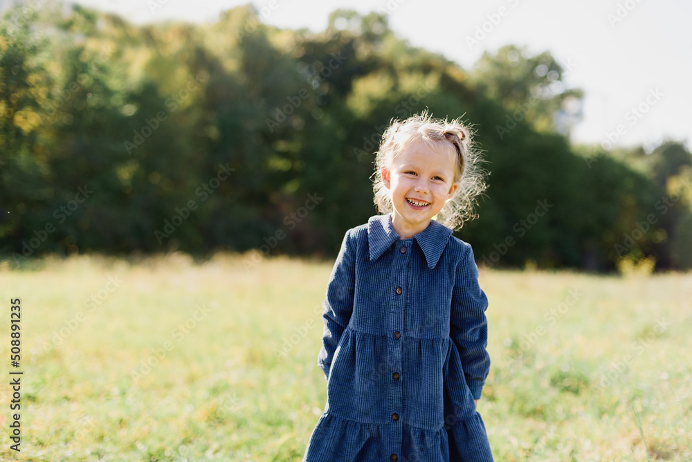 Close up portrait of beautiful little girl with blonde long hair and big blue eyes looking at camera with relaxed expression. Nature background. Close up portrait of beautiful little girl with blonde long hair and big blue eyes looking at camera with relaxed expression. Nature background.