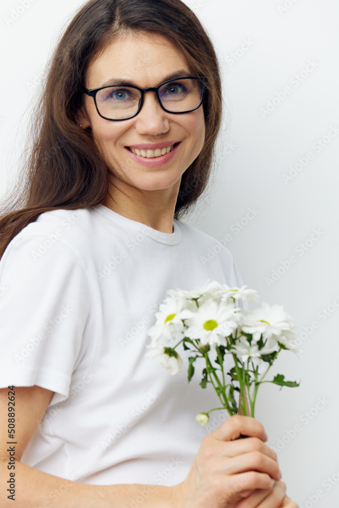 portrait of a beautiful pleasantly smiling woman with long dark hair, wearing glasses and holding a bouquet of chamomile flowers in her hands portrait of a beautiful pleasantly smiling woman with long dark hair, wearing glasses and holding a bouquet of chamomile flowers in her hands