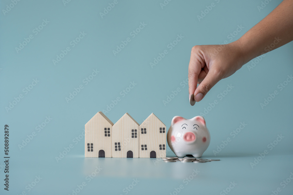 Piggy bank and small wooden house at back concept of savings. Save money to buy , loan , rent the house. - obrazy, fototapety, plakaty 