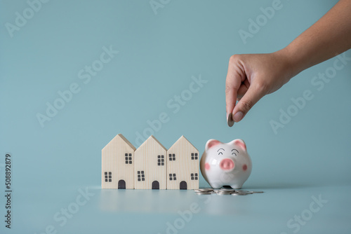 Piggy bank and small wooden house at back concept of savings. Save money to buy , loan , rent the house.