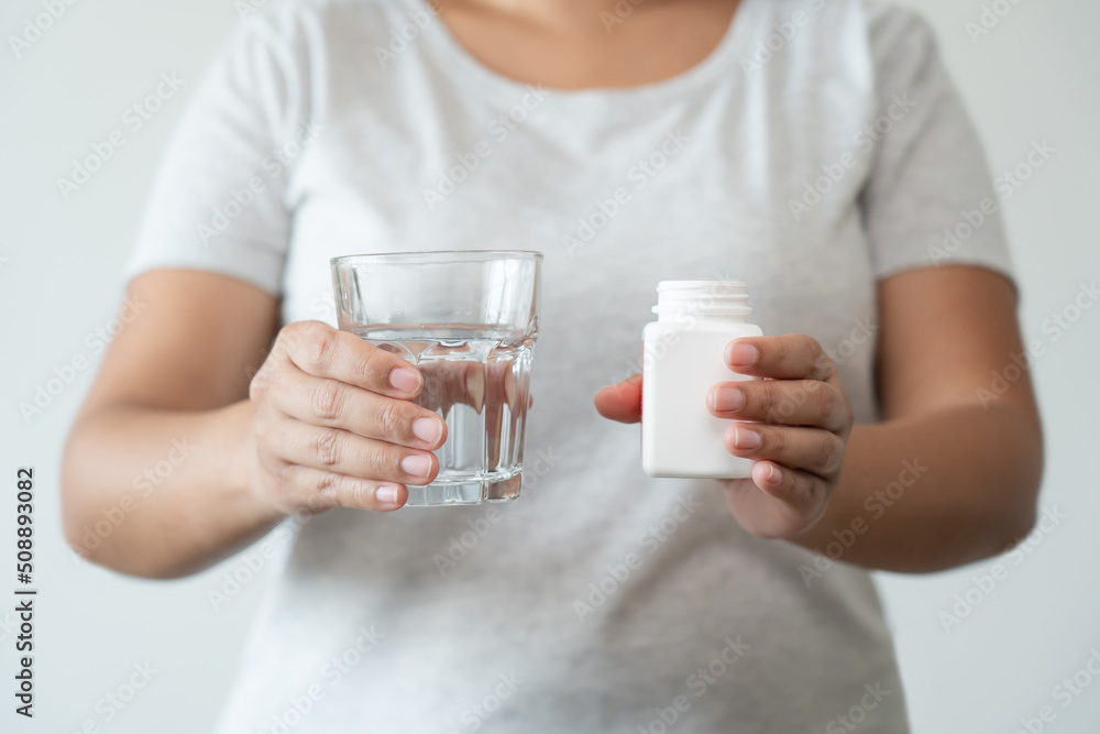 Asian woman close up ready to take supplement pill holding a glass of water. Sick person need medicine and water for good health. Asian woman close up ready to take supplement pill holding a glass of water. Sick person need medicine and water for good health.