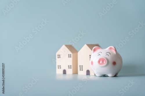 Piggy bank and blurred small wooden house at back concept of savings. Save money to buy , loan , rent the house.