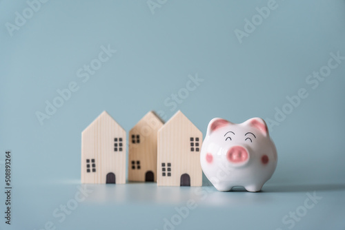 Piggy bank and small wooden house at back concept of savings. Save money to buy , loan , rent the house.