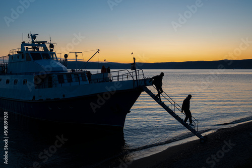 Tourist boat at the pier in the sunset on Lake Baikal. Tourist disembarking.