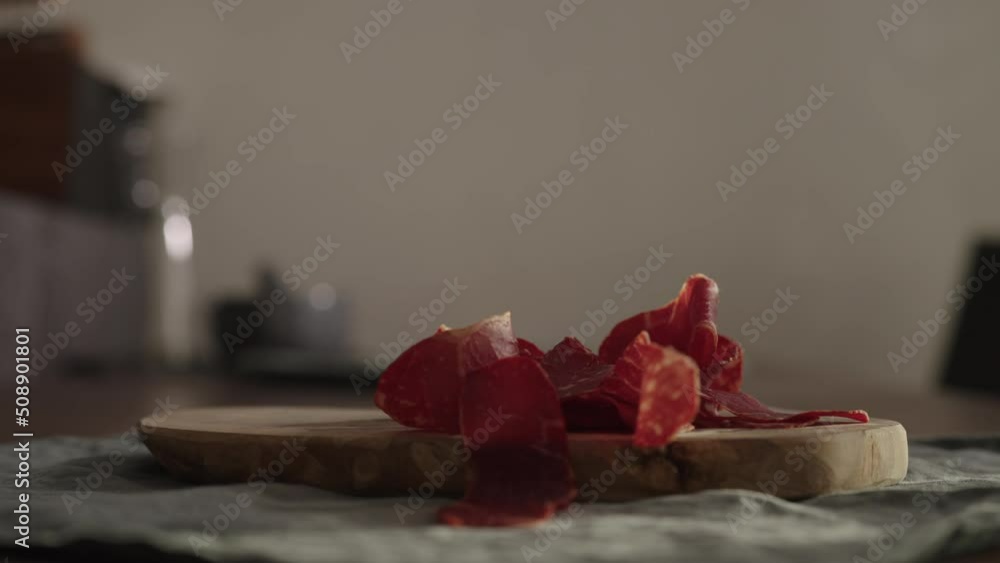Slow motion man takes slices of beef pastrami from olive wood board Slow motion man takes slices of beef pastrami from olive wood board