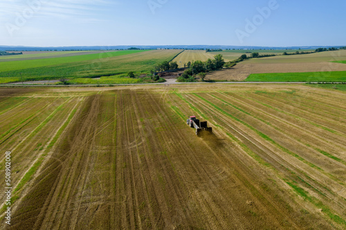 Top view of a tractor scattering manure from a trailer in the field. Work in the field near the road. Countryside.